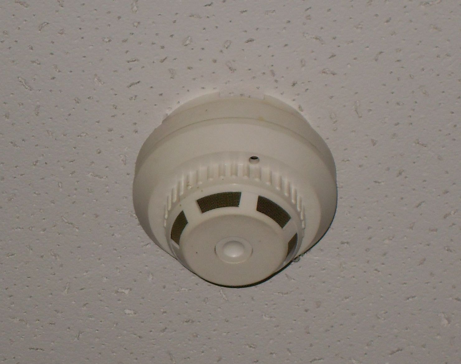 A round white smoke alarm mounted on a textured ceiling
