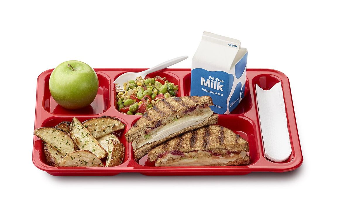 A high school lunch tray from a Maine school district with a grilled sandwich, apple, vegetables and milk