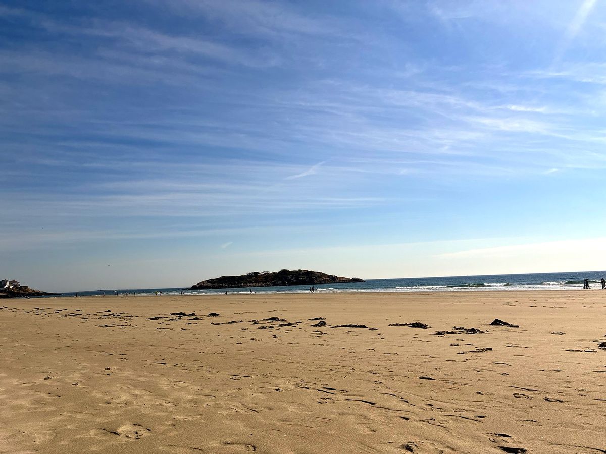 Good Harbor Beach at low tide with Salt Island offshore under a blue sky with thin high clouds