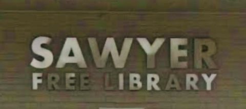 El letrero de Sawyer Free Library en letras blancas en relieve sobre una pared de madera