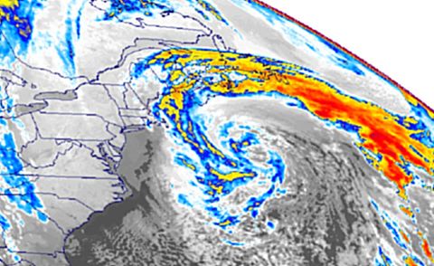 A satellite image in false color shows a large storm spiraling off the Northeast coast of the United States, with bands of red and yellow cloud stretching east over the Atlantic